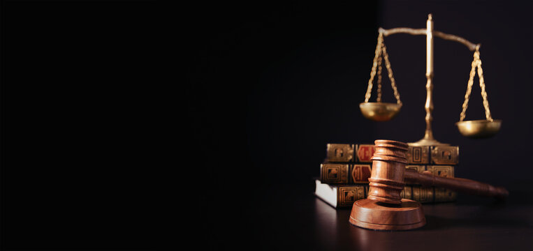 Gavel and scales on law books against a dark background